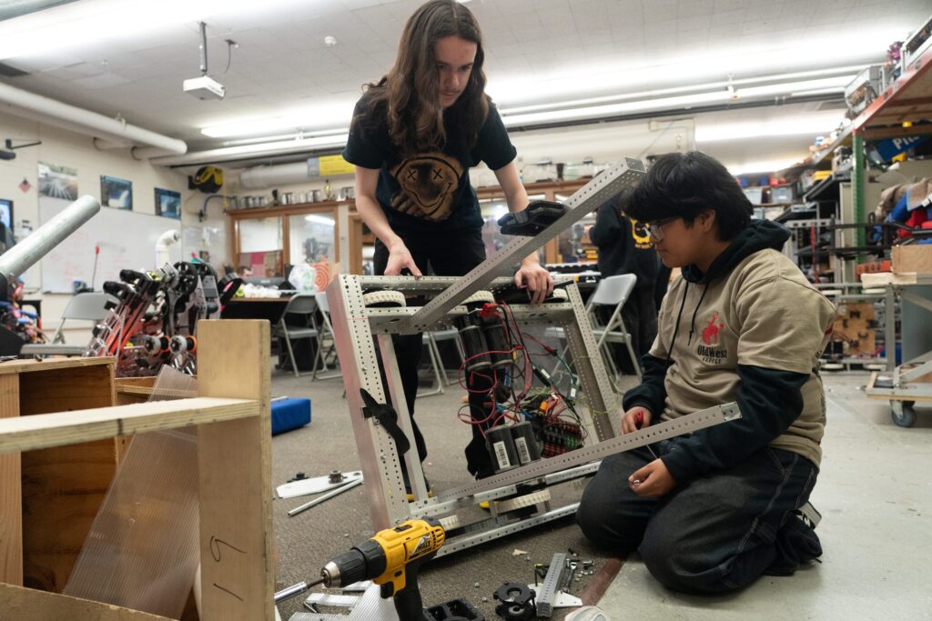 Students assembling an aluminum robot frame in the robotics shop